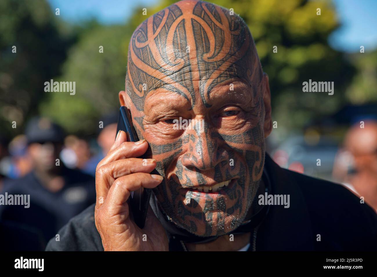 Maori man with tattoos with his mobile phone during Waitangi Day. Waitangi Day is the national day of New Zealand, and commemorates the signing, on 6 Stock Photo
