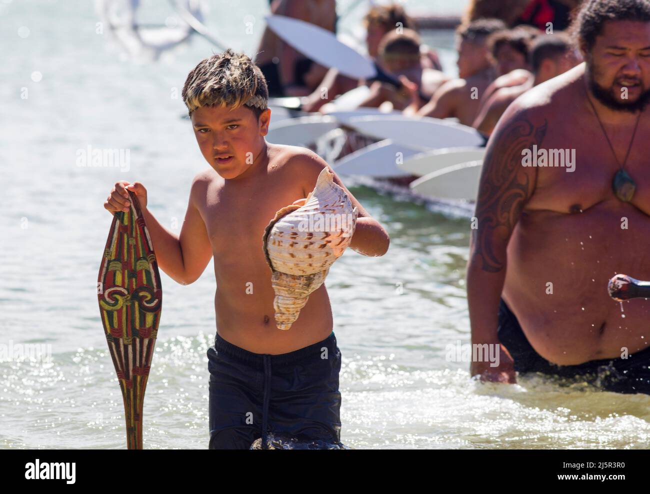 Maori boy leaves a Waka taua (war canoe) in Waitangi Day celebrations in Waitangi Various Māori traditions recount how their ancestors set out from th Stock Photo