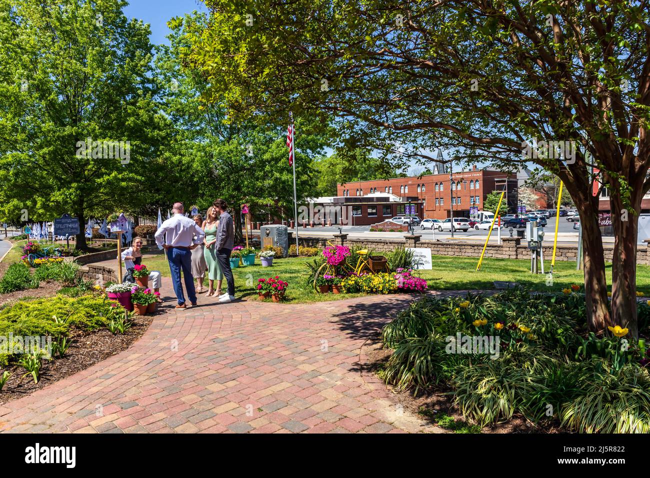MOORESVILLE, NC, USA-17 APRIL 2022: Friends socializing in the Mooresville city park on a sunny, spring Easter Sunday.  Colorful scene with flowers an Stock Photo