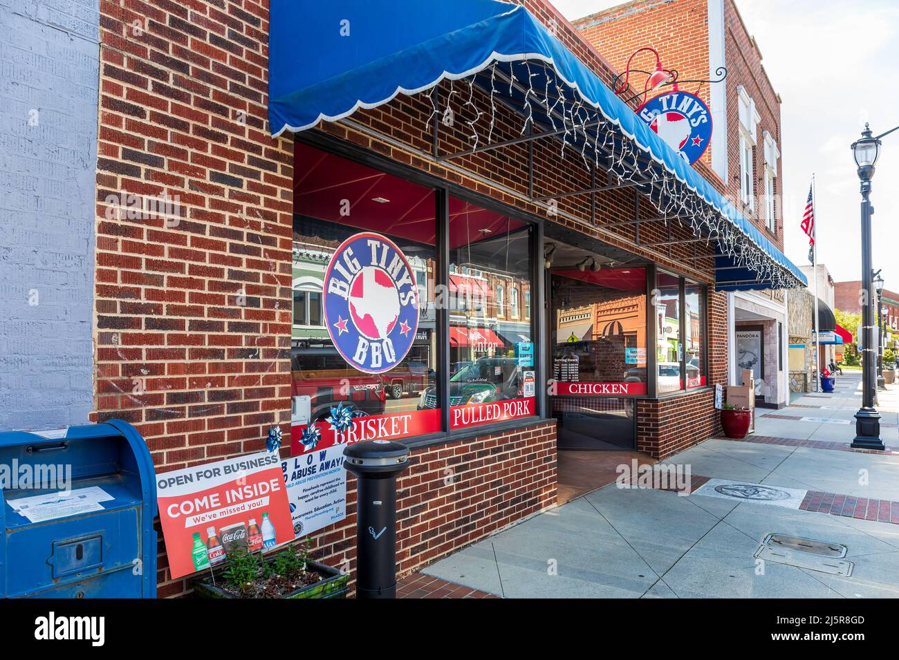 MOORESVILLE, NC, USA-17 APRIL 2022: Big Tiny's BBQ. Diagonal perspective of store front, with view down sidewalk. Stock Photo