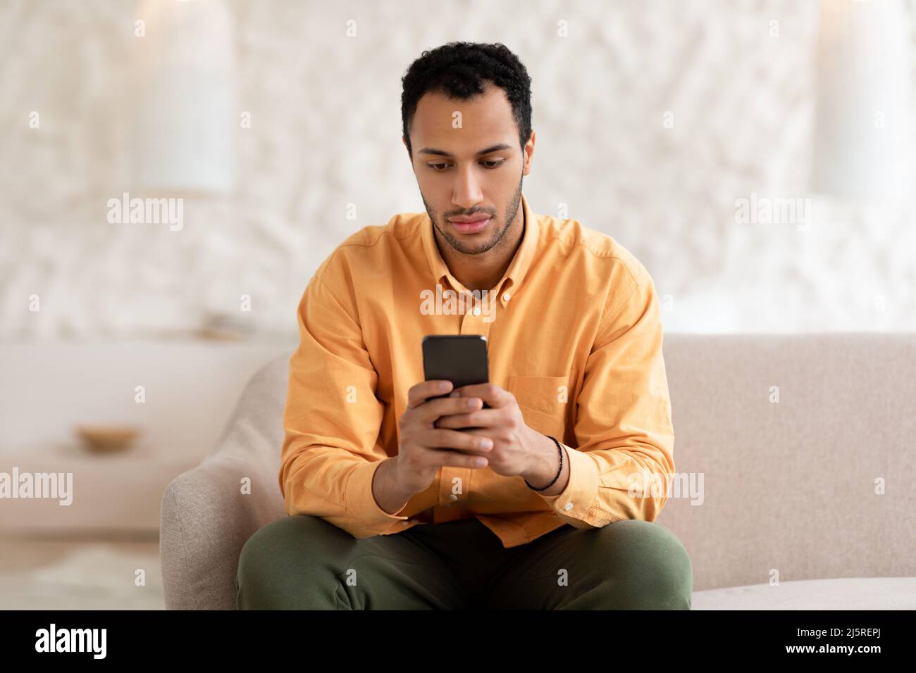 Young man using smart phone at home Stock Photo
