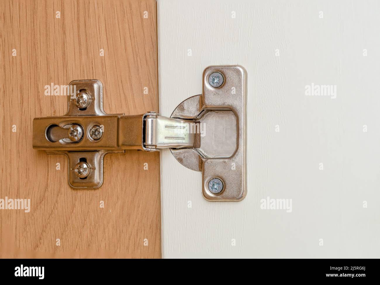 close up of a concealed steel hinge fitted into a kitchen cabinet Stock Photo