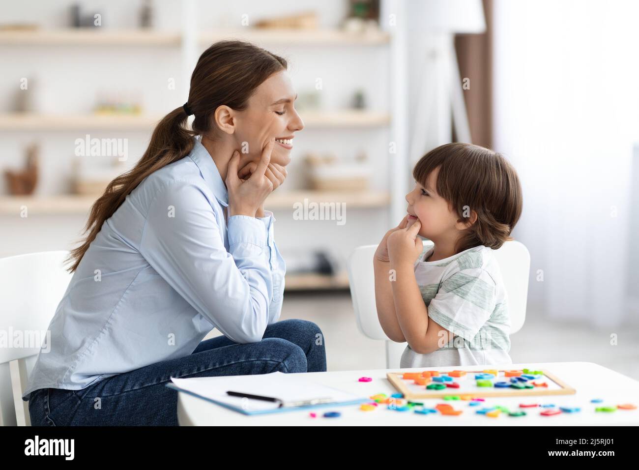 Professional woman specialist training with cute little boy, showing