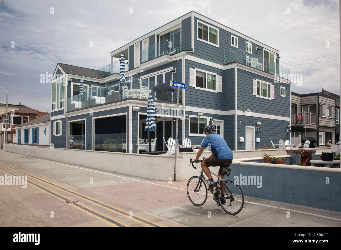 Man riding a bicycle on Ocean front Walk in front of the beautiful summer holiday houses, Mission Bay , San Diego Stock Photo