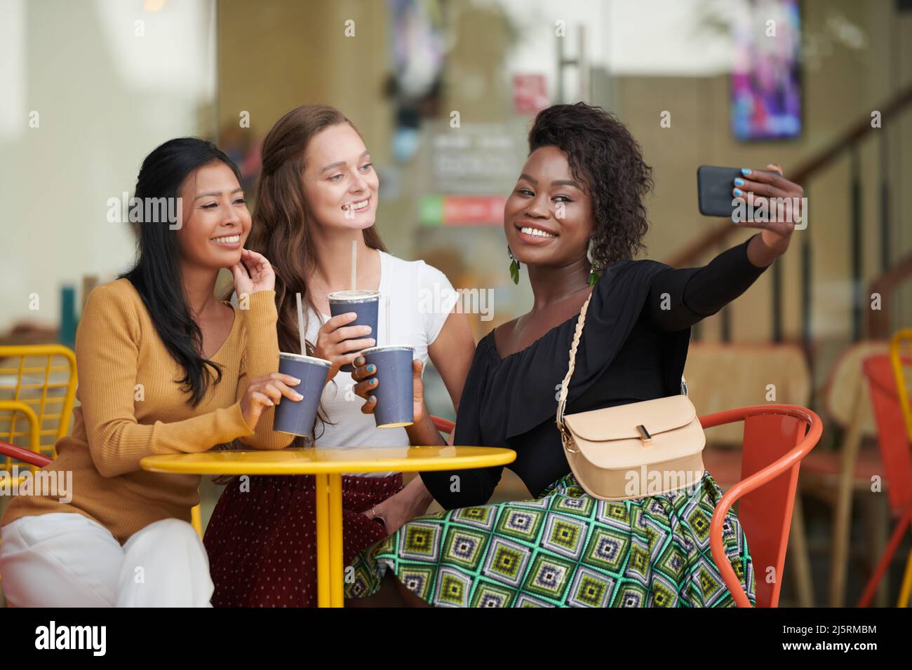 Сheerful african american young woman in summer dress and choker necklace  at cafe drinking milkshake cocktail Stock Photo - Alamy