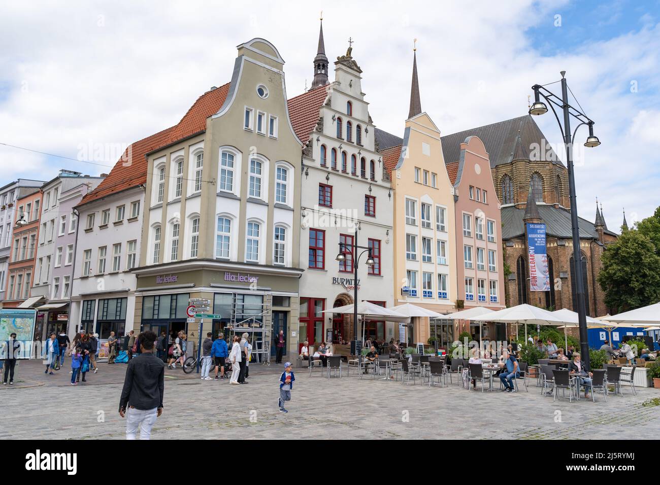 Historical building facades on the new market in the city. People in the town are having a great time. Beautiful architecture for tourism. Stock Photo
