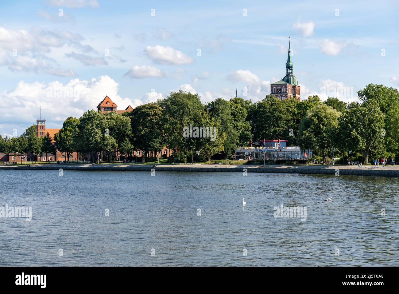 Cityscape with the Baltic Sea in the foreground. A beautiful hanseatic town on a sunny summer day. The blue sky is covered with small white clouds. Stock Photo