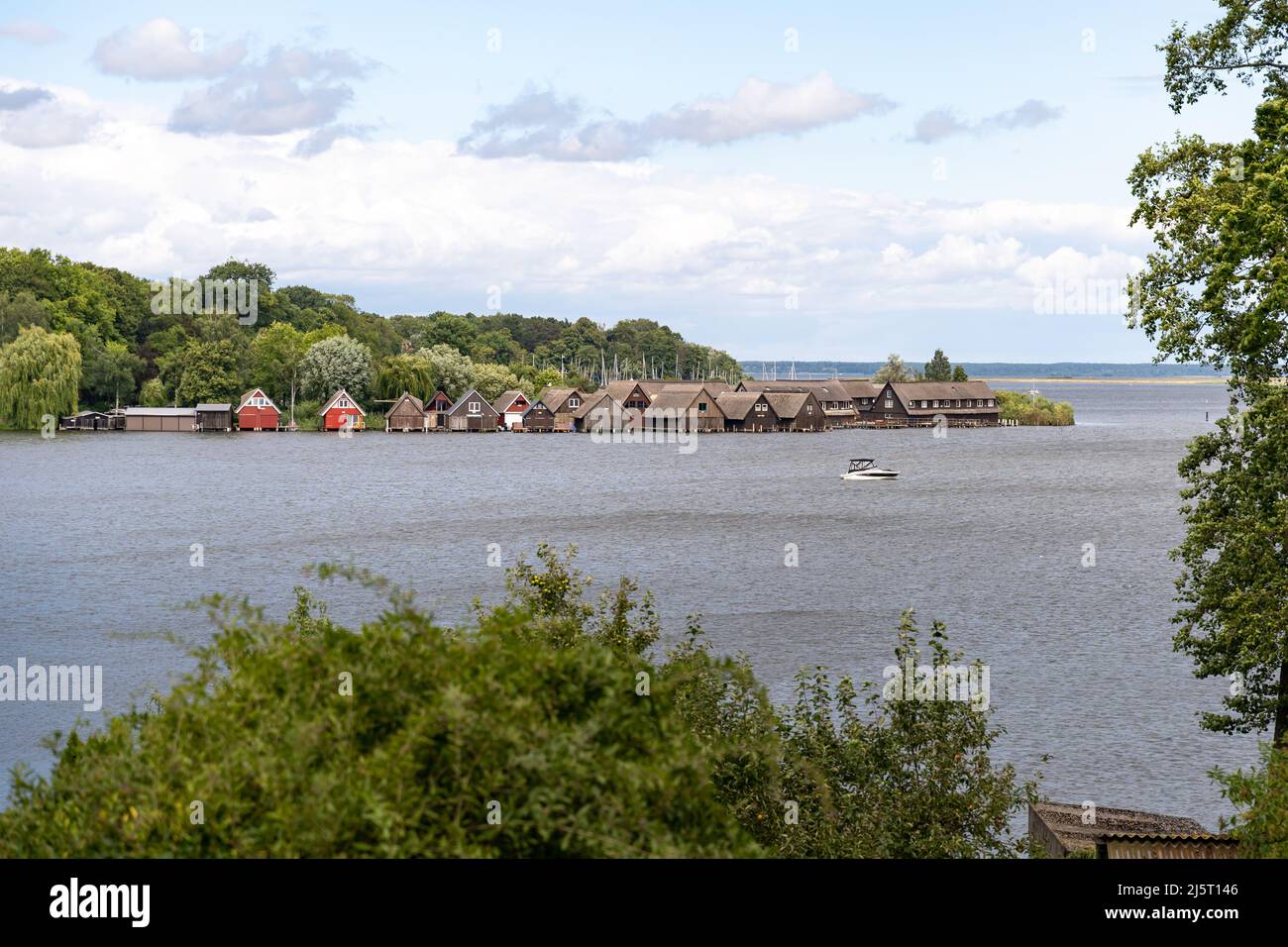 Small port in Röbel Müritz. Landscape view with small wooden buildings next to the water. A small boat is in the front of the harbour. Stock Photo