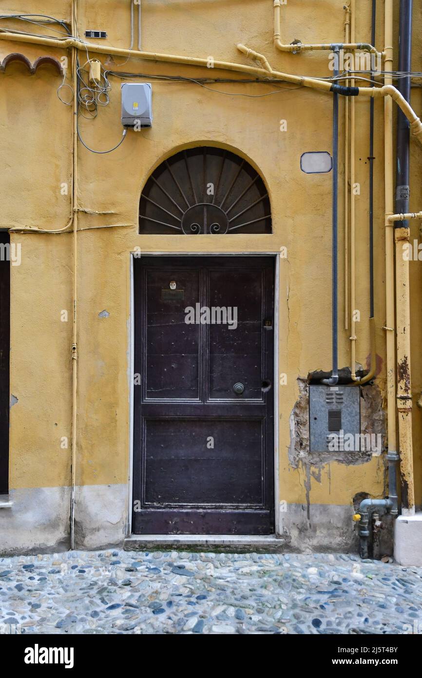 Detail of the exterior of an old house with a wooden door and a gas meter in the wall, Sanremo, Imperia, Liguria, Italy Stock Photo