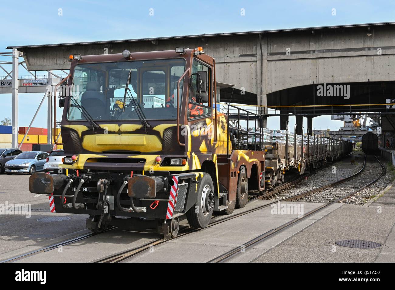 Basel, Switzerland - April 2022: Specialist road rail vehicle being used to shunt a heavy train carrying metal ingots in the city's port on the Rhine Stock Photo