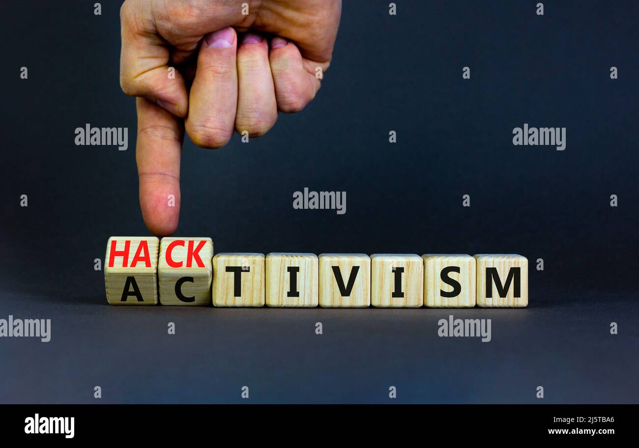 Activism or hacktivism symbol. Businessman turns wooden cubes and changes the word Activism to Hacktivism. Beautiful grey table grey background, copy Stock Photo