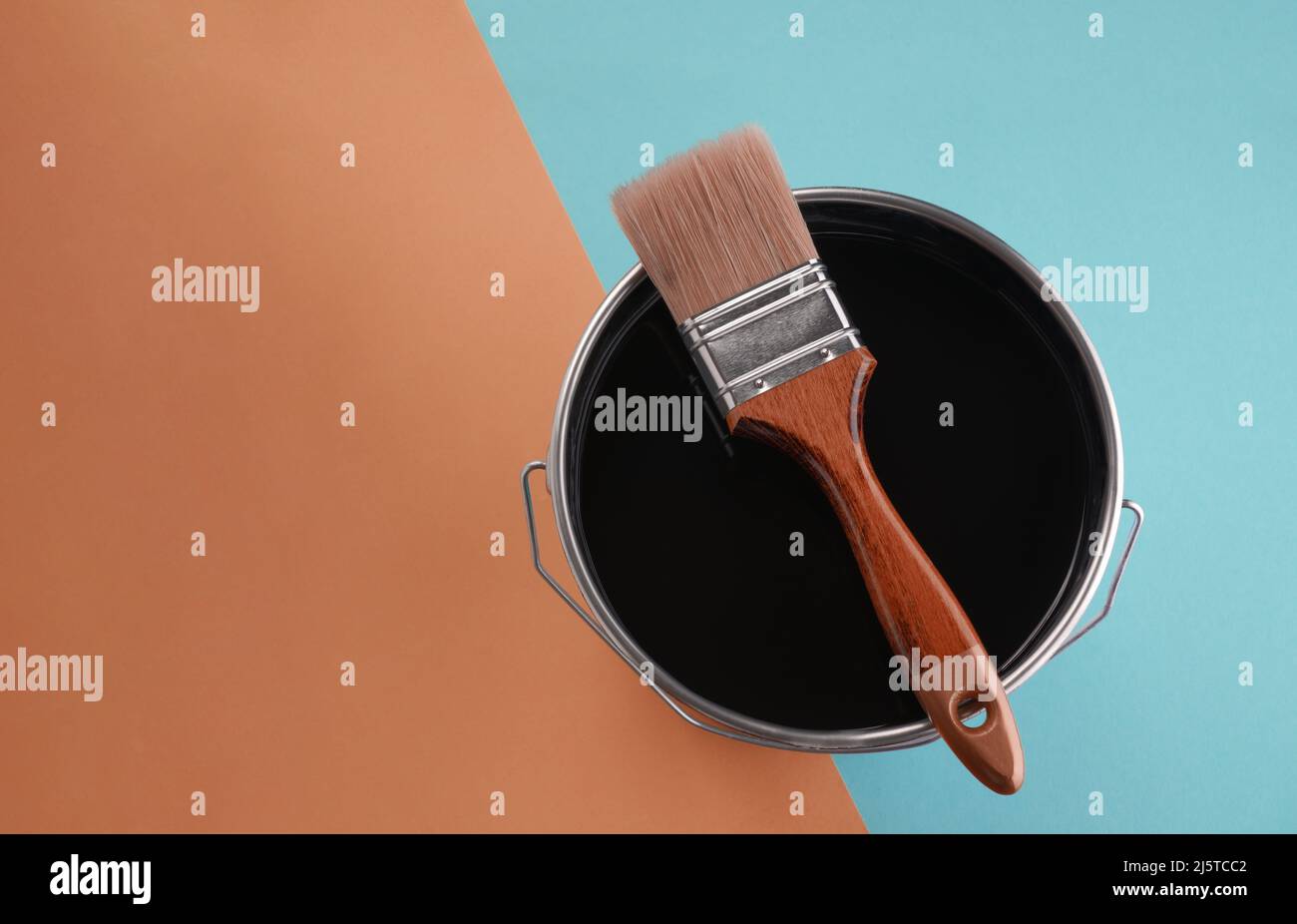Top view of paintbrush on paint can on blue and orange background Stock Photo