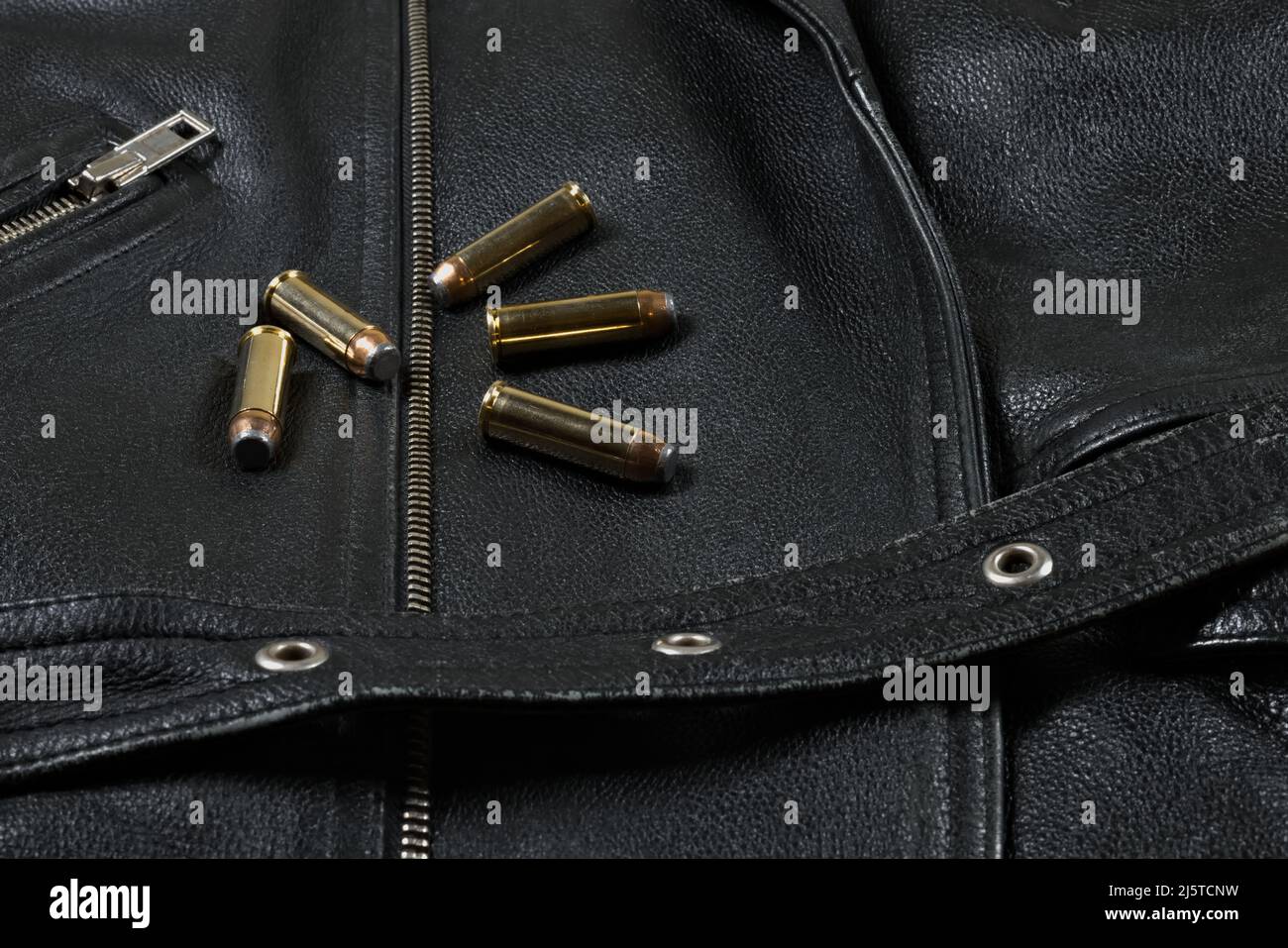 five .44 magnum revolver cartridges lying on a black leather background (biker jacket) Stock Photo