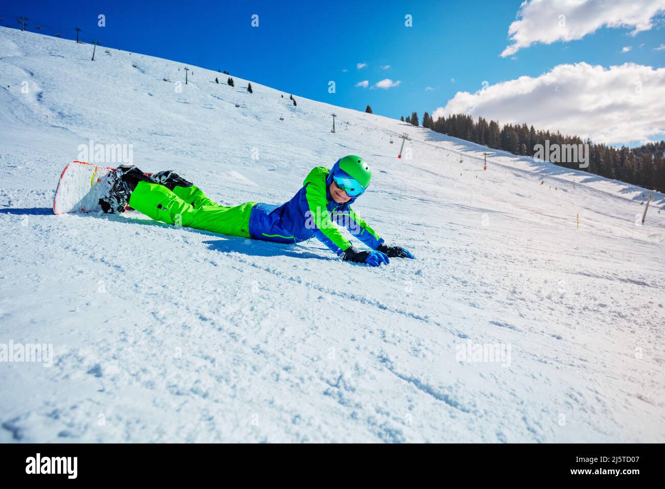 Boy with snowboard lay on the ski slope Stock Photo