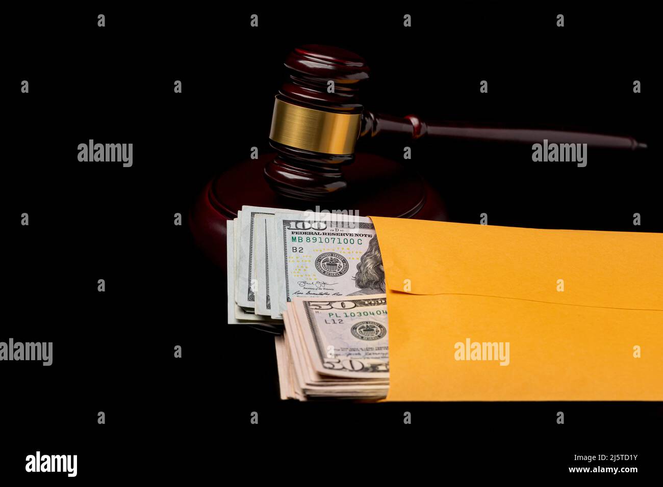Courtroom gavel and cash money in envelope. Bribe, government corruption and corrupt legal system concept. Stock Photo