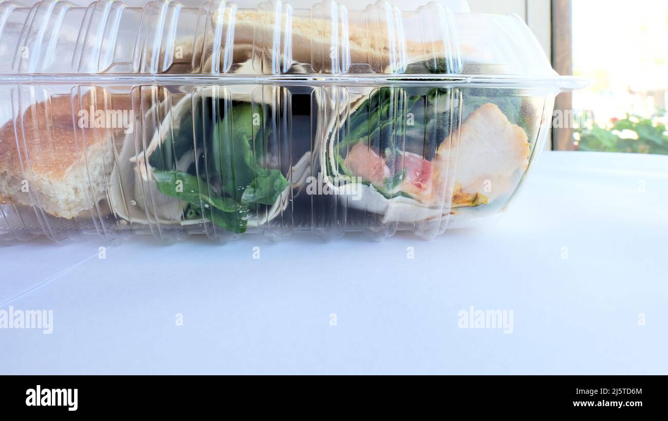 Clear plastic leftover container with a chicken and hummus wrap