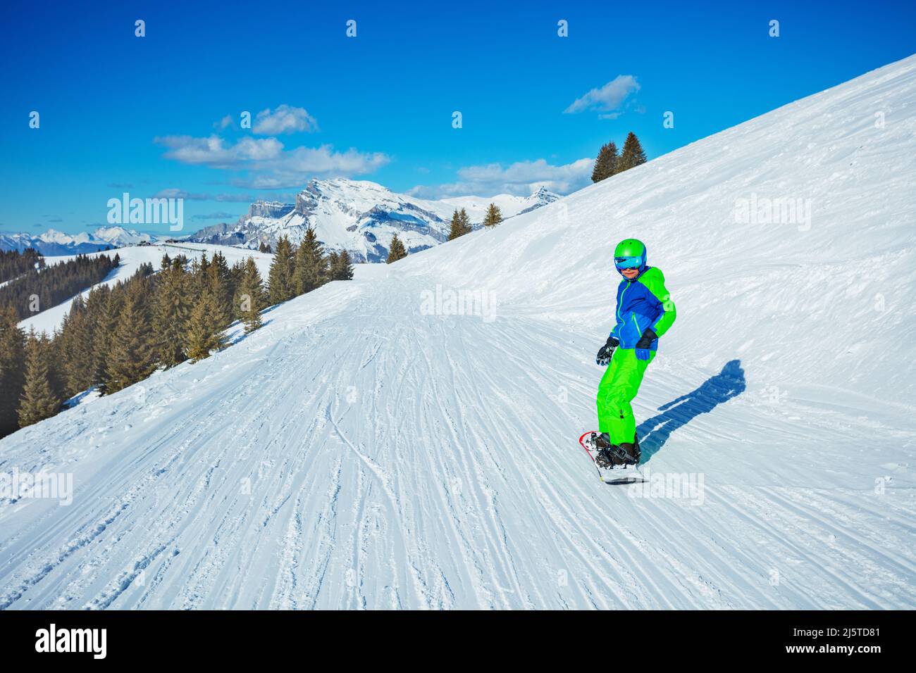 Boy slide on snowboard from mountain, looking to the camera Stock Photo