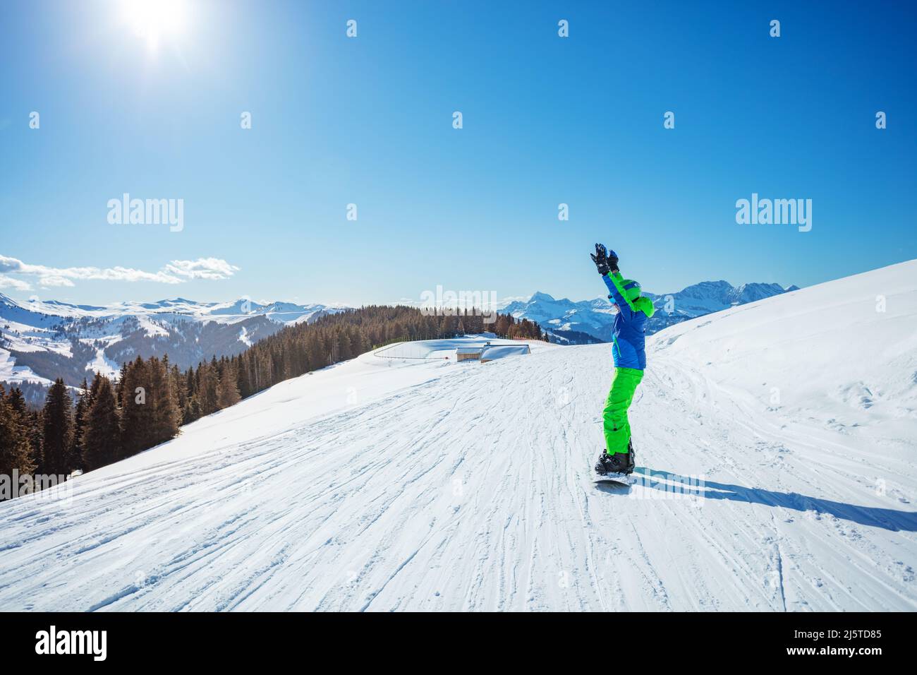 Snowboarder boy with snowboard on the track lifting hands up Stock Photo