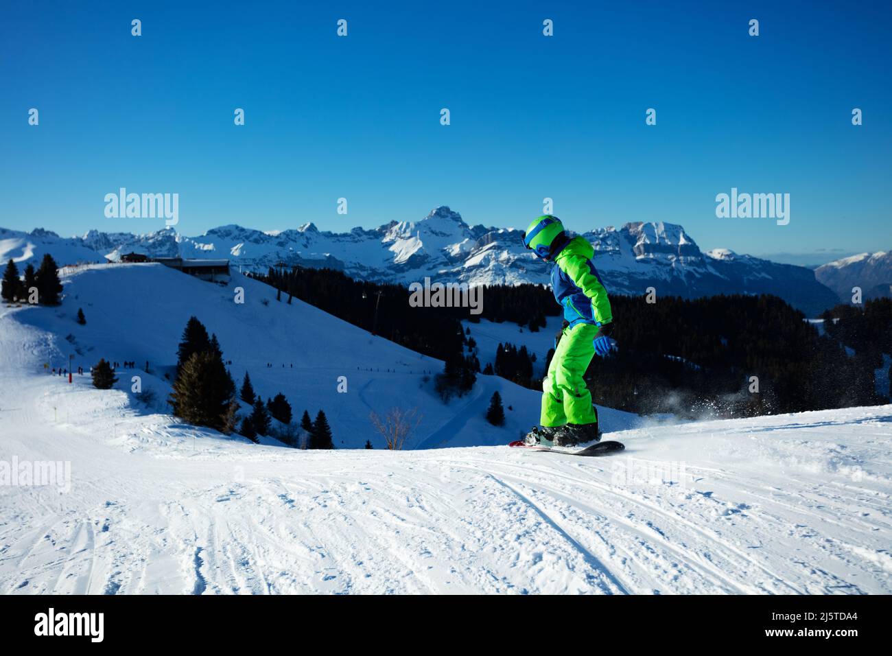 Boy going down ski slope on snowboard from the mountain Stock Photo