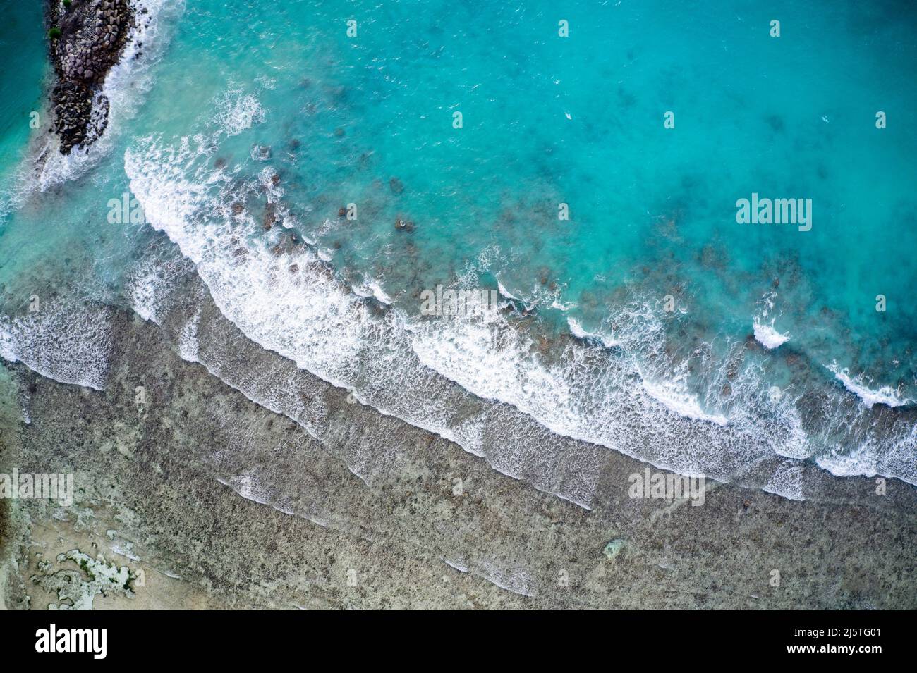 Drone field of view of waves crashing into beach and sand in tropical island paradise of Seychelles. Stock Photo