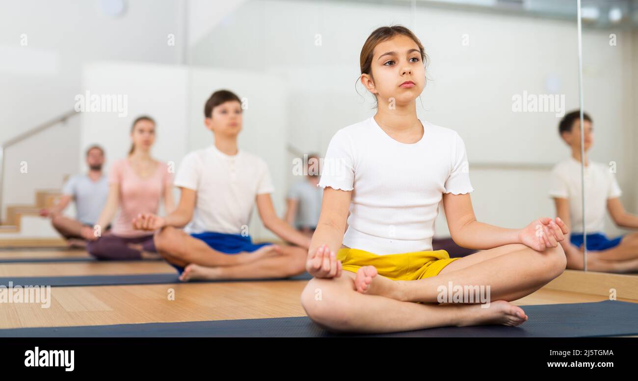 Girl exercising lotus pose during family yoga training Stock Photo - Alamy