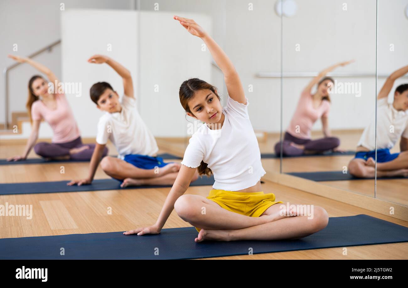 Girl exercising lotus pose during family yoga training Stock Photo - Alamy
