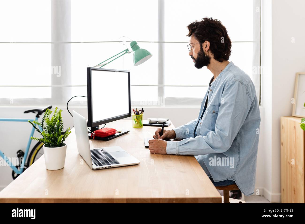 Professional young creative designer using graphic tablet and laptop computer Stock Photo