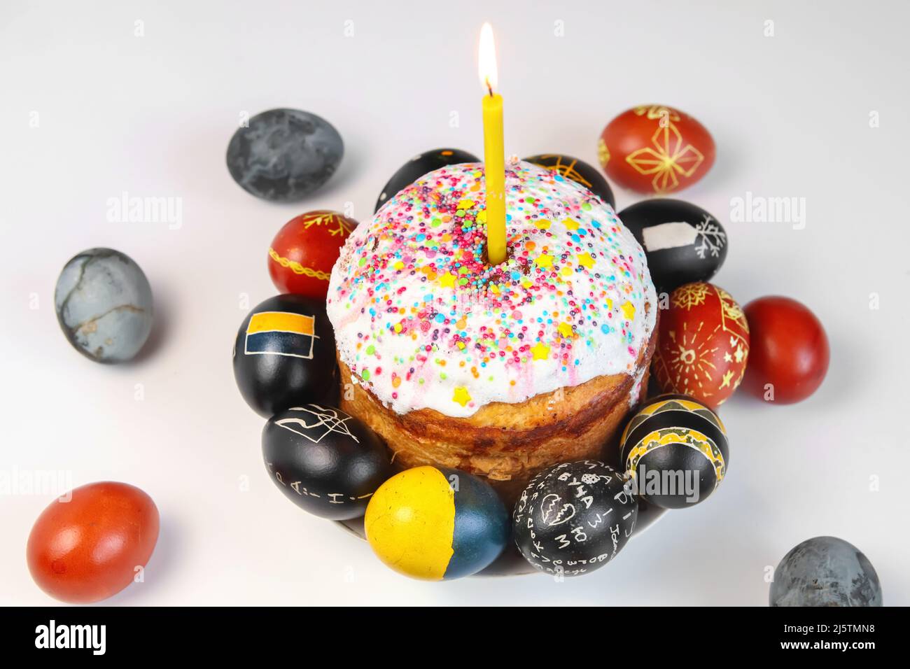 Defocus Easter table setting. Easter cake craffin. Close up Easter eggs pastel colored on white background. Minimal Easter celebration concept, dyed c Stock Photo