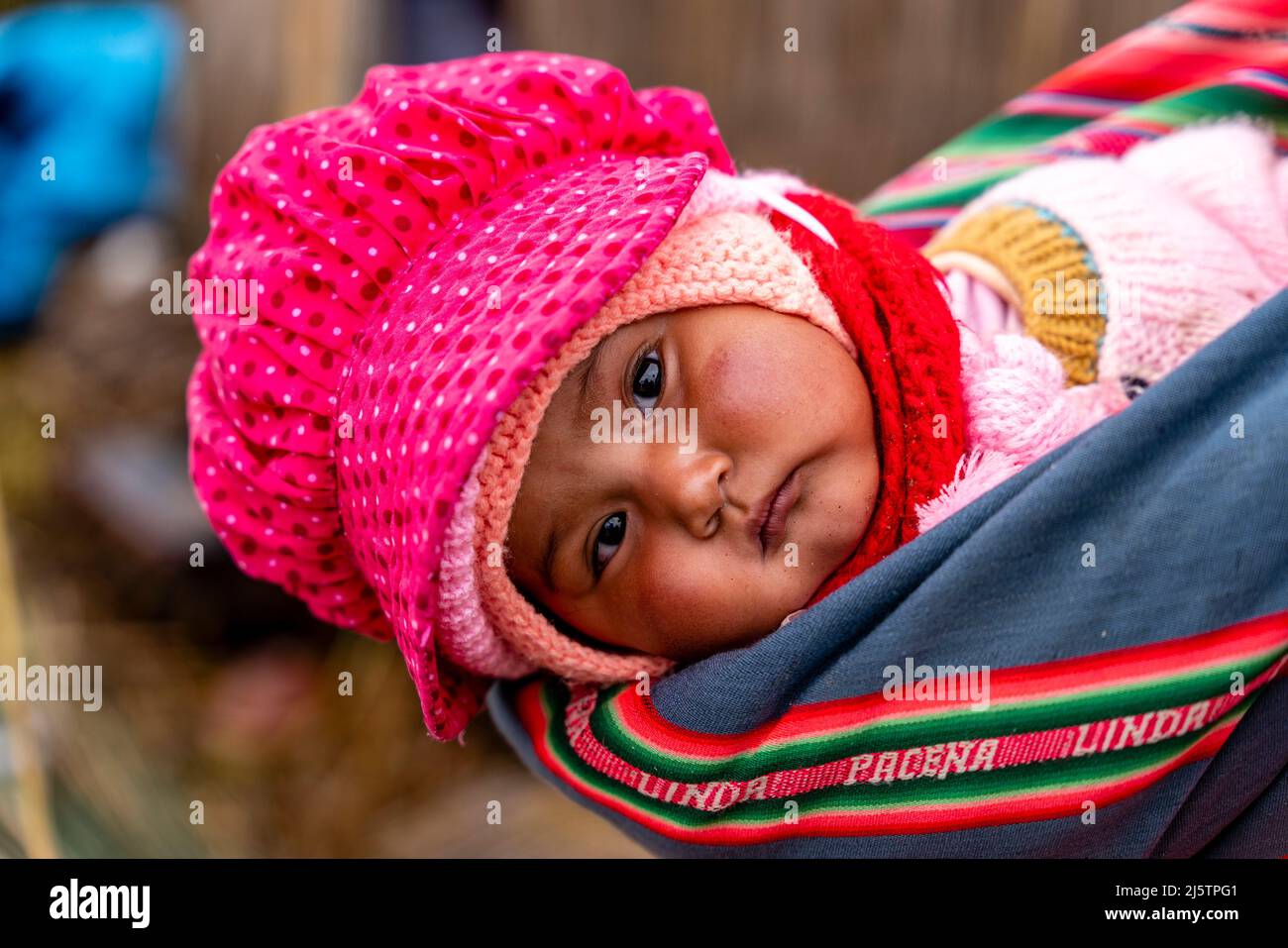 An Uros Baby being Carried In A Sling On The Uros Floating Islands, Lake Titicaca, Puno, Peru. Stock Photo