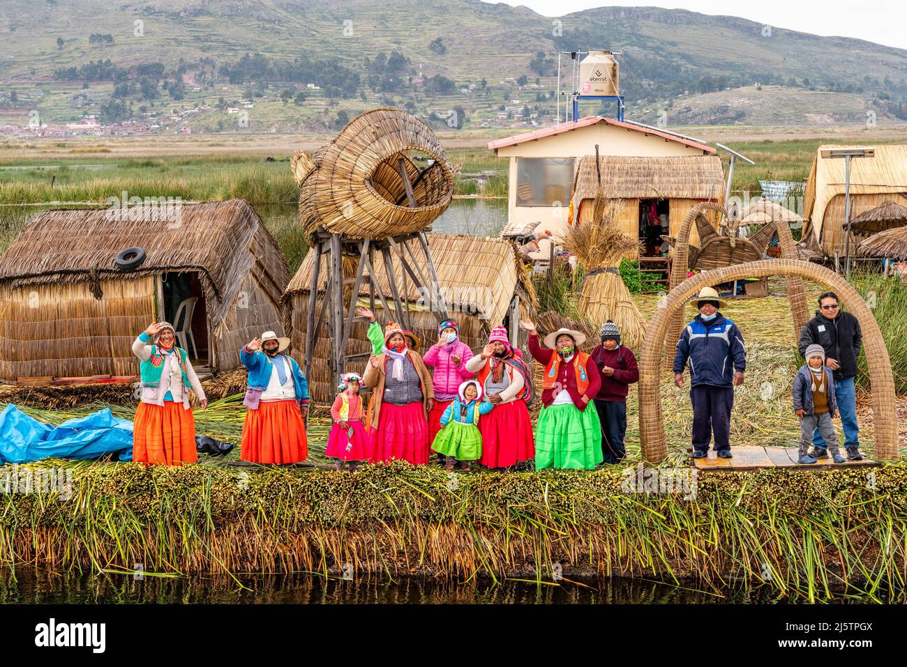 Uros Islanders Waving At A Tourist Boat From The Uros Floating Islands, Lake Titicaca, Puno, Peru. Stock Photo