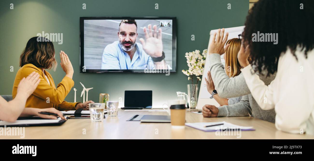 Diverse businesspeople waving a greeting during a video conference. Group of innovative business professionals collaborating on a renewable energy pro Stock Photo