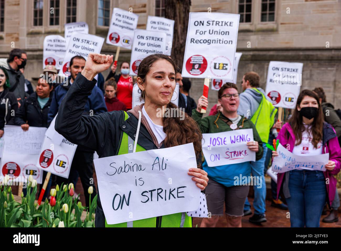 Bloomington, United States. 25th Apr, 2022. Sabina Ali holds a sign with his name on it as members of the Indiana Graduate Workers Coalition and their supporters picket while striking for union recognition in Bloomington. Last week the Indiana University provost threatened to fire the striking grad workers, so the grad workers showed up at the office of the provost with their names and dared the provost to fire them. The graduate workers were unhappy about low wages and paying fees when the union was formed. The strike began on April 13, 2022. Credit: SOPA Images Limited/Alamy Live News Stock Photo