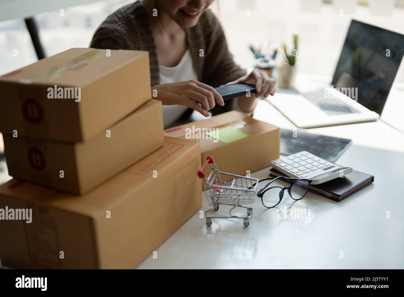 Young asian businesswoman owner packing and take a photo on cardboard box, Young Owner Woman Start up for Business Online. People with online shopping Stock Photo