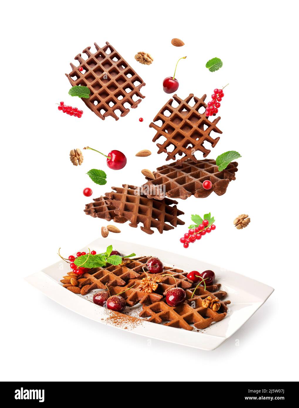 Plate with flying chocolate waffles, berries and nuts on white ...