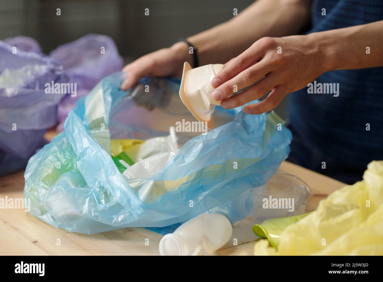 Hand of adolescent guy putting white small plastic yoghurt container ...