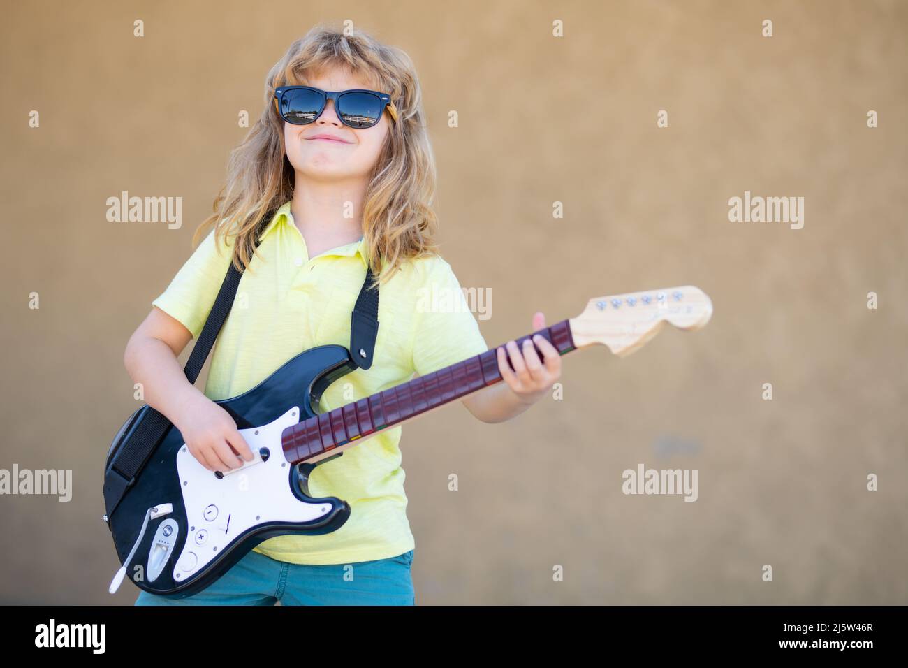 Funny rock child with guitar. Little boy in sunglasses. Child musician