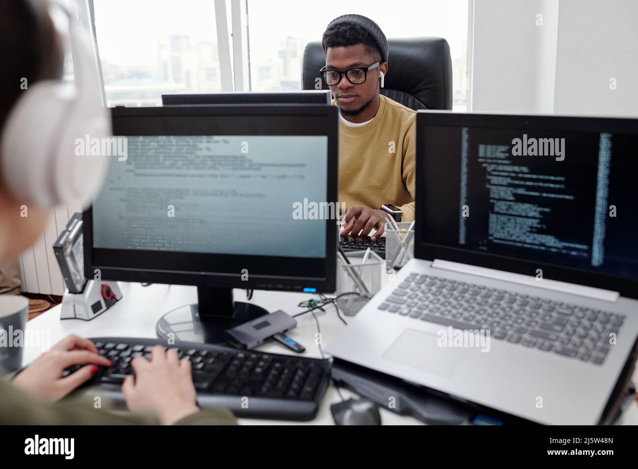 Young serious male programmer looking at computer screen during network ...