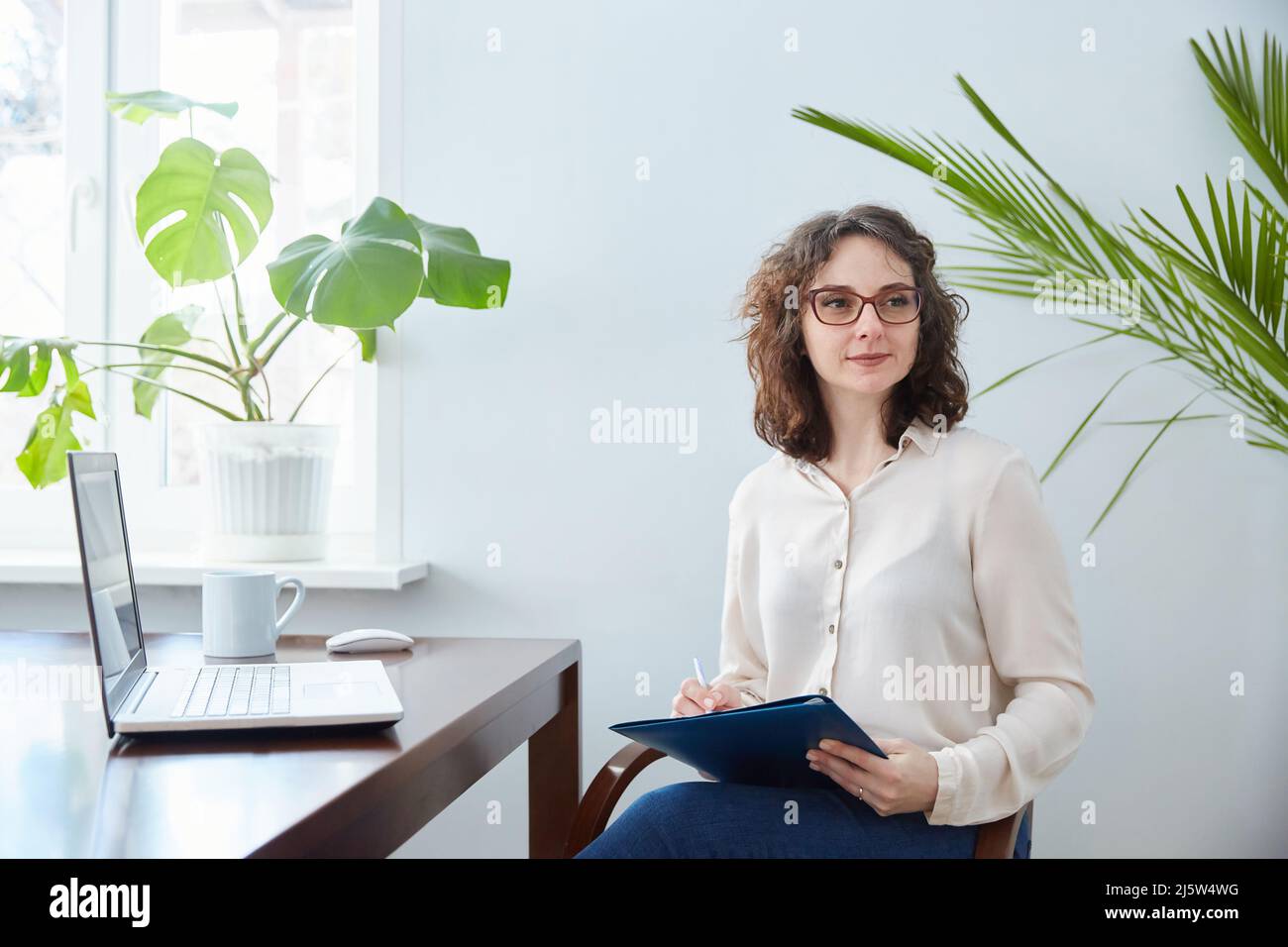 A female psychologist listens to a client and writes down information. Stock Photo