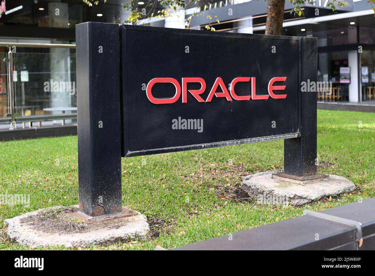 Black Oracle Corporation sign, with red lettering typical of the company's logo, on a patch of grass outside an office building Stock Photo