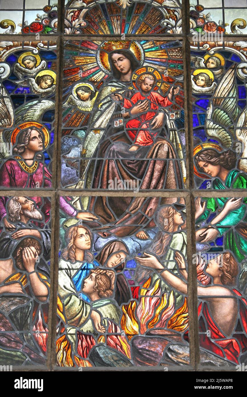 Stained Glass Window Showing Madonna and Jesus With Angels and Last Judgement - People Burning In Fires Of Hell Below Stock Photo