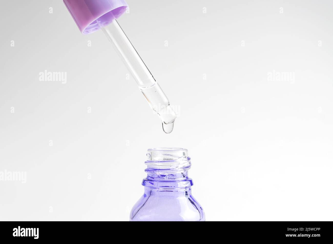 Pipette with dose of fluid hyaluronic acid on white background. Cosmetics concept. Skin care