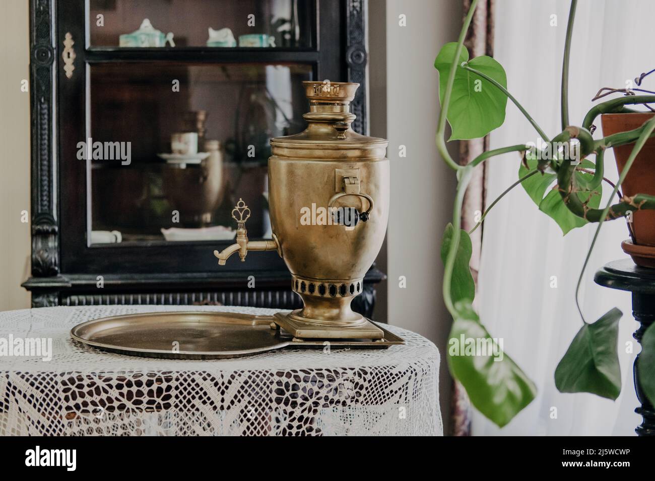 Russian samovar on a table with a tablecloth, against the background of a pantry Stock Photo