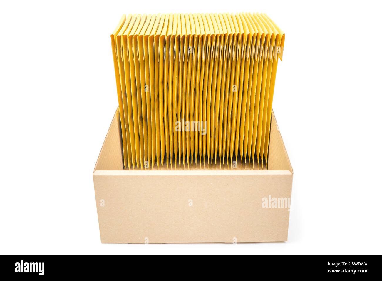 Vertical stack of yellow bubble mailers in a low cardboard box isolated