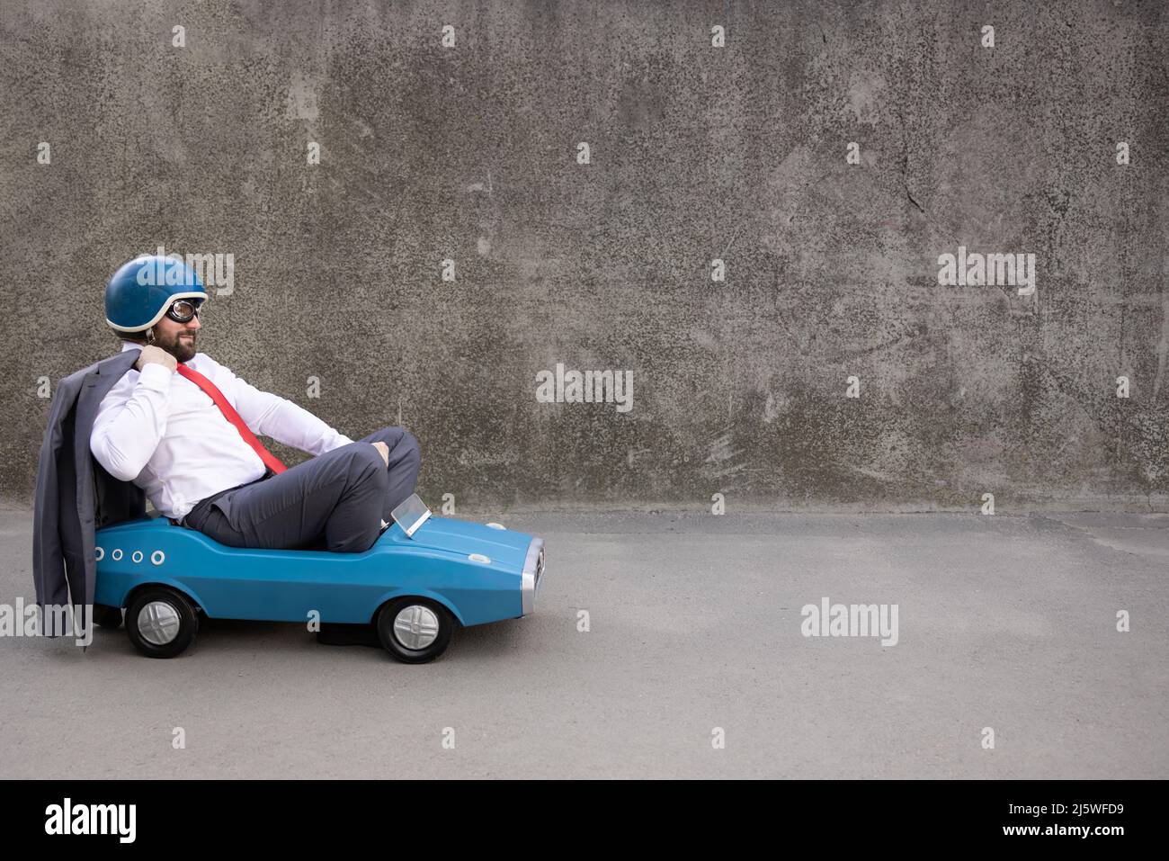 Portrait of funny businessman outdoor. Man driving retro pedal car ...