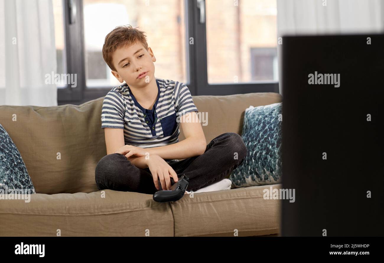 sad boy with gamepad playing video game at home Stock Photo