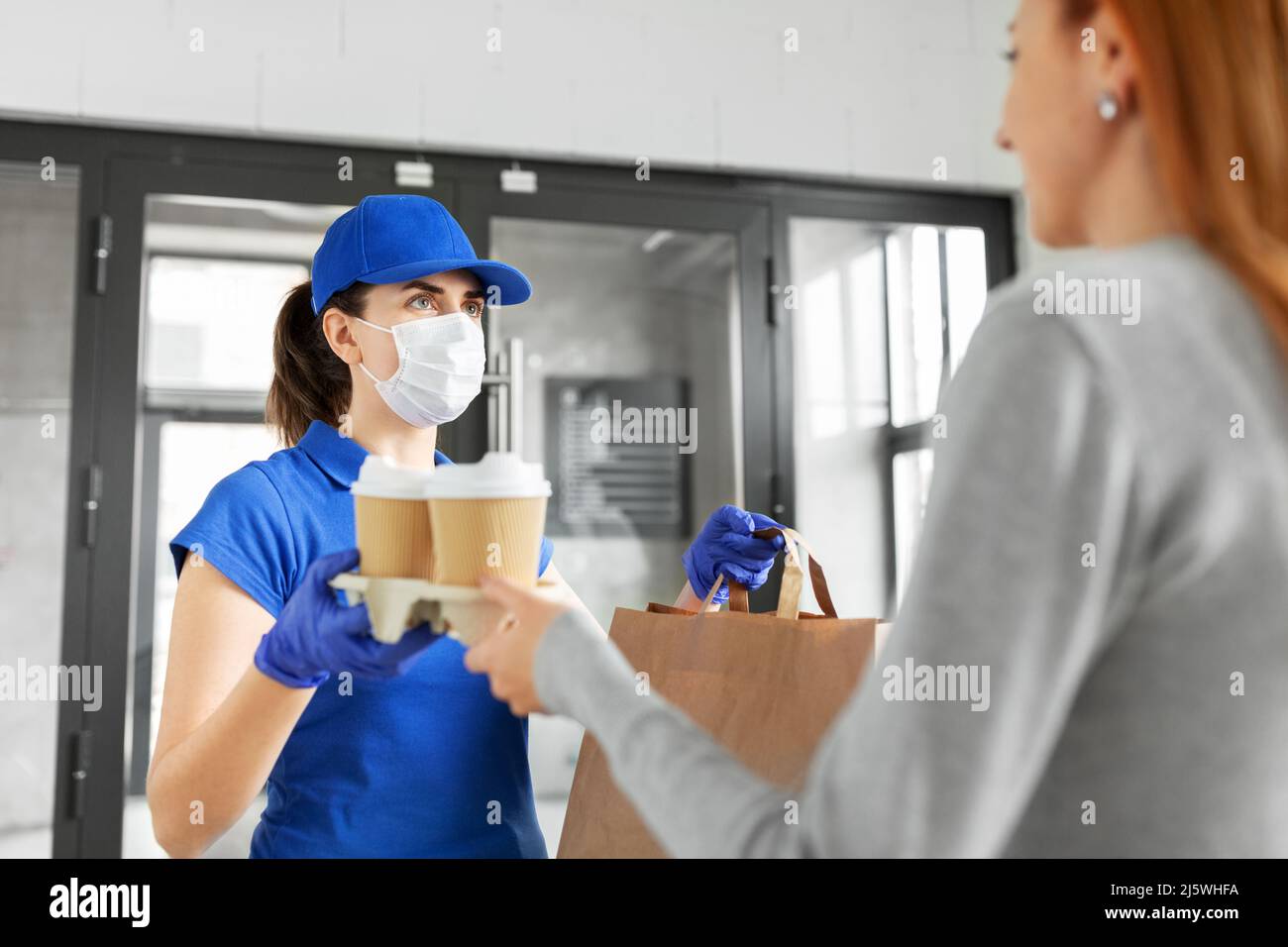 delivery girl in mask giving paper bag to customer Stock Photo - Alamy