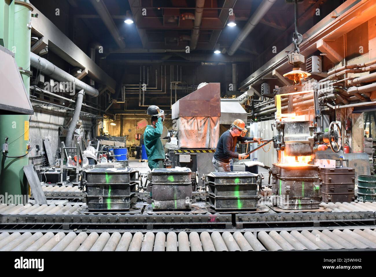 group of workes in a foundry - production in steelworks - industrial building inside Stock Photo