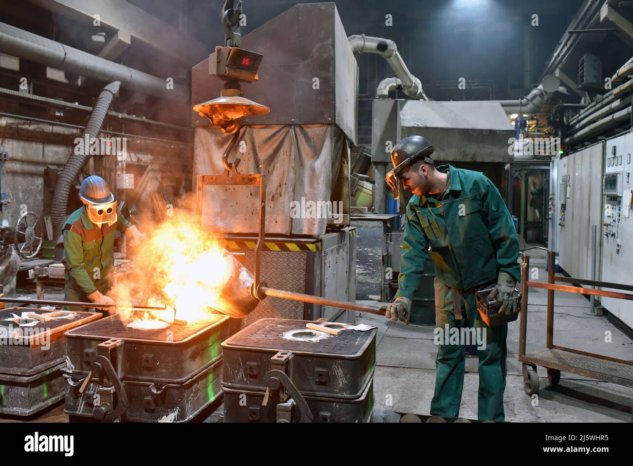 workers in a foundry casting a metal workpiece - safety at work and teamwork - closeup prhoto Stock Photo