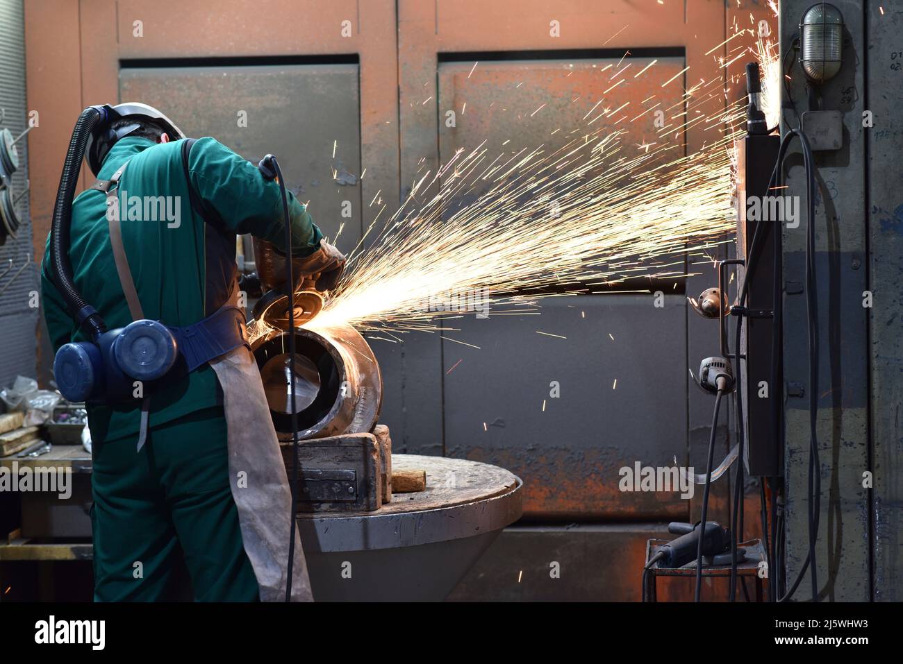 workers in safety clothing sanding a casting in an industrial company Stock Photo
