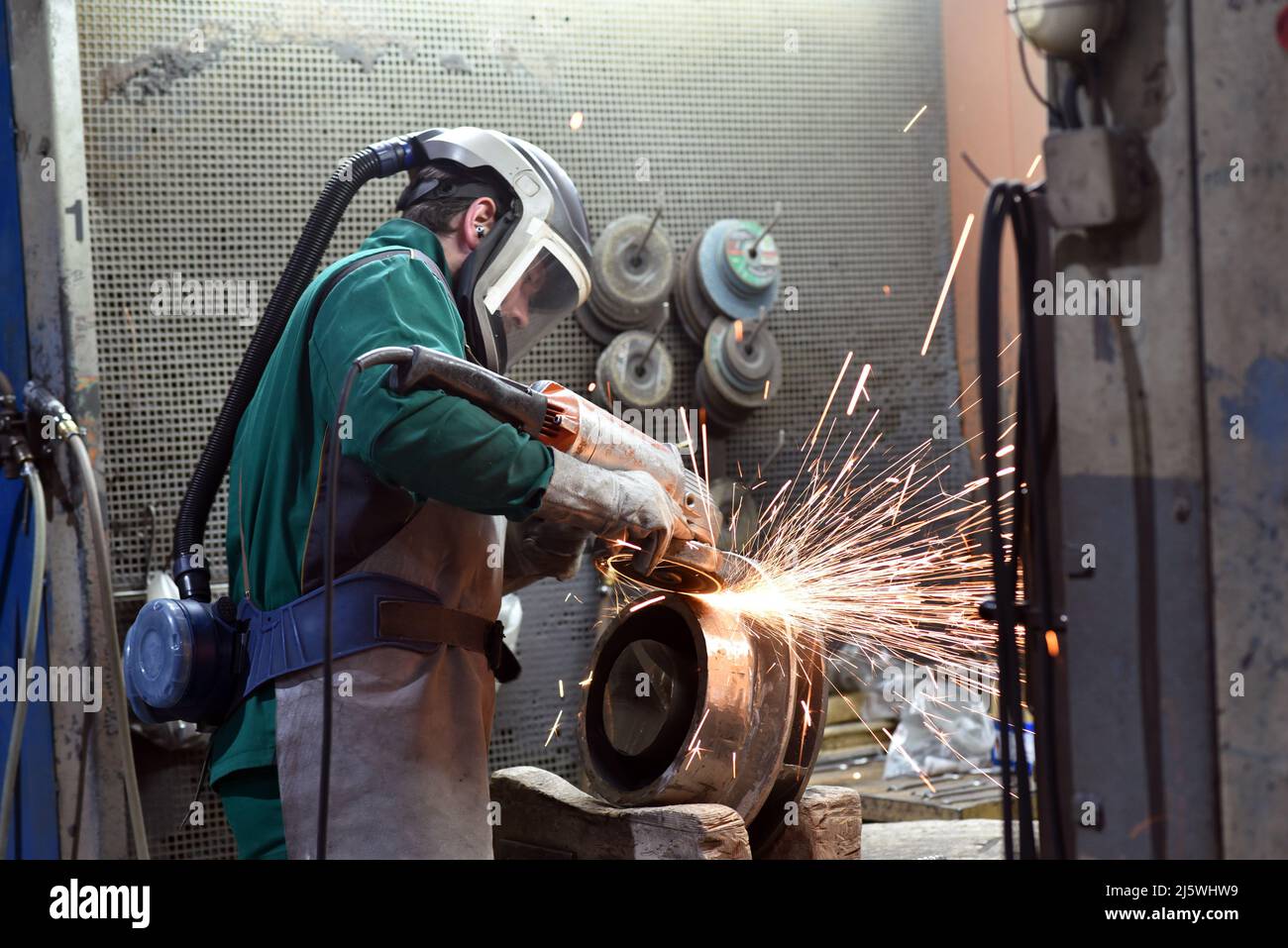 workers in safety clothing sanding a casting in an industrial company Stock Photo